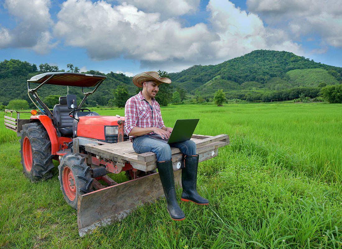 Service Center - Farmer Sits on a Tractor Using a Laptop